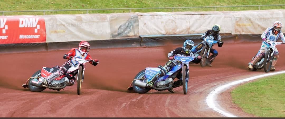 Vier Speedway-Fahrer in Kurvenlage auf der Rennbahn – Zeidler unterstützt den Sport